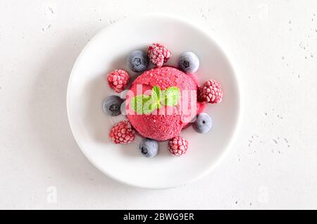 Himbeer-Sorbet auf Platte auf Steinhintergrund. Kaltes Dessert im Sommer. Draufsicht, flaches Lay Stockfoto