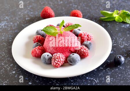 Himbeer-Sorbet auf Platte auf dunklem Steinhintergrund, Nahaufnahme Stockfoto