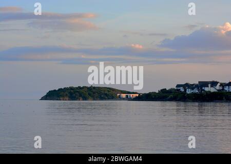 Barry, Wales, der Damm und Punkt auf Barry Island am Horizont. Flut mit Sonnenuntergang und Wolken über dem Himmel verstreut. Stockfoto