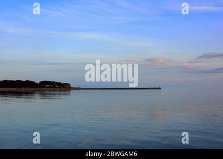 Barry, Wales, der Damm und Punkt auf Barry Island am Horizont. Flut mit Sonnenuntergang und Wolken über dem Himmel verstreut. Stockfoto