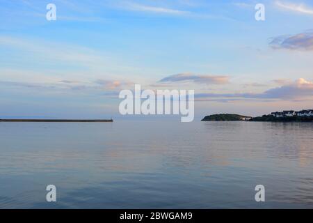 Barry, Wales, der Damm und Punkt auf Barry Island am Horizont. Flut mit Sonnenuntergang und Wolken über dem Himmel verstreut. Stockfoto