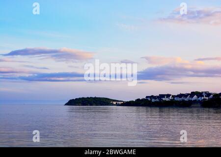 Barry, Wales, der Damm und Punkt auf Barry Island am Horizont. Flut mit Sonnenuntergang und Wolken über dem Himmel verstreut. Stockfoto