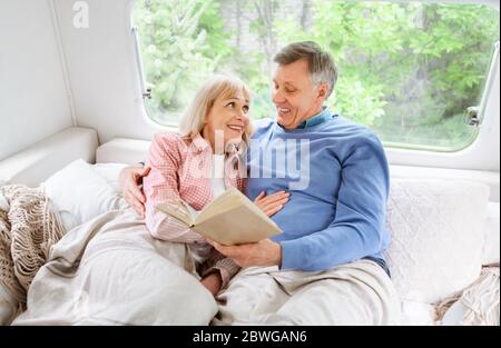 Loving reifen Paar Lesen Buch auf dem Bett im Wohnmobil während der Familienreise Stockfoto