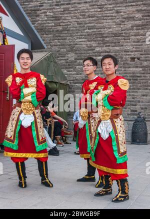 Xian, China - 30. April 2010: Begrüßungszeremonie vor dem Nordtor der Stadtmauer von Shuncheng. Nahaufnahme von 3 jungen Mann in rotem Tracht. Gra Stockfoto