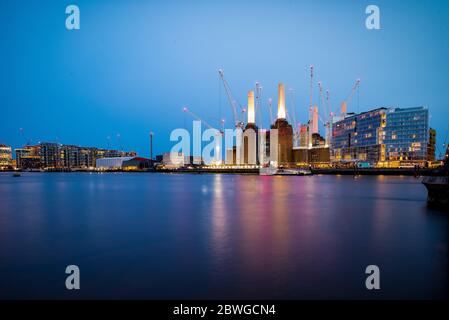 Blick auf die Abenddämmerung von der anderen Seite der Themse auf das Regenerationskonzept des Kraftwerks Battersea während des Baus, mit Kränen. Stockfoto