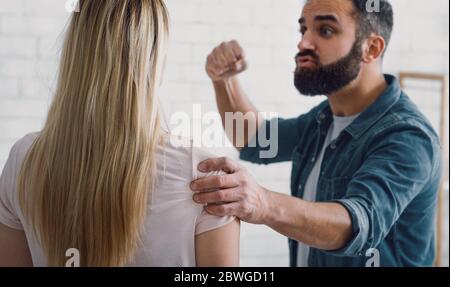 Gewalt in der Familie. Wütender Mann schwingt die Faust auf die Frau Stockfoto