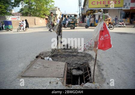 Pendler passieren in der Nähe eines offenen Kanalisation Hauptloch, das jeden Unfall verursachen kann, was die Nachlässigkeit der betroffenen Abteilungen zeigt, in Anum Sanam Chowk auf Gulbahar in Peshawar am Montag, 1. Juni 2020. Stockfoto