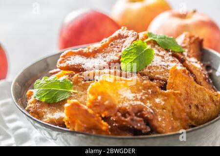 Fein gebratene Apfelpfannkuchen, bestreut mit Vanillezucker und Zimt, gekrönt mit Minzblättern Stockfoto