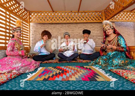 Usbekische Musiker in traditioneller Kleidung, die Musikinstrumente spielen und lokale Lieder singen, in Chiwa, Usbekistan Stockfoto