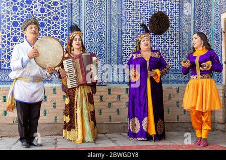 Usbekische Musiker in traditioneller Kleidung, die Musikinstrumente spielen und lokale Lieder singen, in Chiwa, Usbekistan Stockfoto