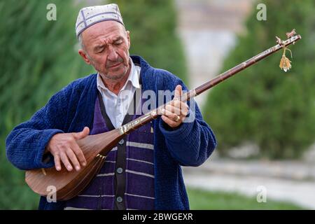 Usbekischer Mann spielt lokale Musikinstrument, bekannt als Dutar, in Samarkand, Usbekistan Stockfoto