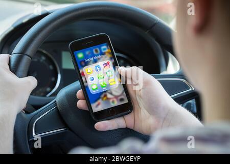 Teenager Fahrer SMS und Blick auf Social Media auf seinem Handy während der Fahrt in Großbritannien. (Bild nach Modell gestellt)