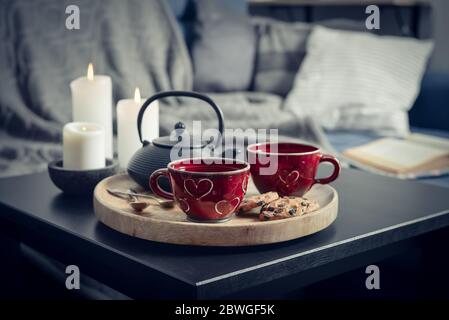 Zwei Tassen Tee auf einem Serviertablett auf dem Couchtisch. Frühstück auf dem Sofa in der Morgensonne. Gemütliches Herbst- oder Winterkonzept. Stockfoto