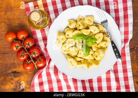 Tortellini Pasta. Italienische gefüllte Pasta mit Basilikumblättern auf dem Teller. Draufsicht. Stockfoto