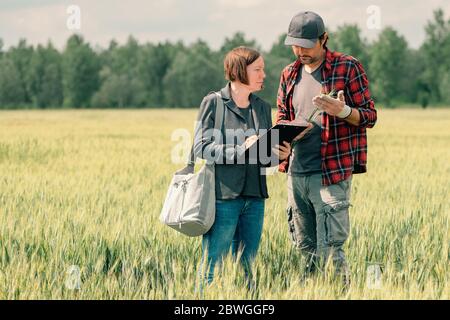 Hypothek Darlehen Officer Unterstützung Landwirt in finanziellen Zuschuss Antragsprozess, Bankier und Landarbeiter in Weizenfeld. Stockfoto