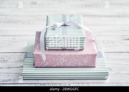 Stapel Geschenkboxen mit grauem Band auf weißem Holzhintergrund Stockfoto
