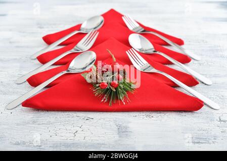 Rote Servietten in Form eines Weihnachtsbaums mit Gabeln und Löffeln auf Holzhintergrund Stockfoto
