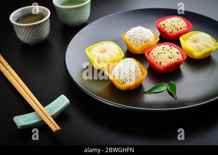 Mochi-Sortiment auf Teller mit Essstäbchen und grünem Tee - traditionelles japanisches Reisdessert, Nahaufnahme Stockfoto