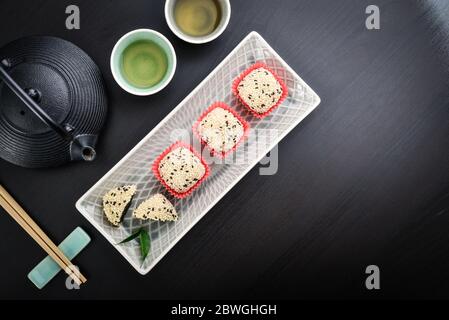 Mochi-Sortiment auf Teller mit Essstäbchen und grünem Tee - traditionelles japanisches Reisdessert, Draufsicht Stockfoto