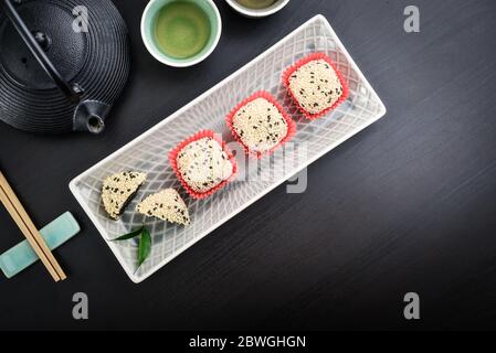 Mochi-Sortiment auf Teller mit Essstäbchen und grünem Tee - traditionelles japanisches Reisdessert, Draufsicht Stockfoto