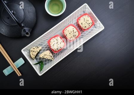 Mochi-Sortiment auf Teller mit Essstäbchen und grünem Tee - traditionelles japanisches Reisdessert, Draufsicht Stockfoto