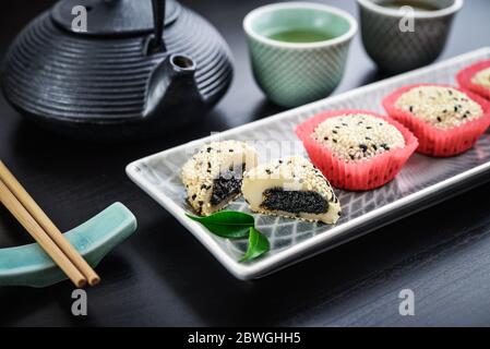 Mochi-Sortiment auf Teller mit Essstäbchen und grünem Tee - traditionelles japanisches Reisdessert, Nahaufnahme Stockfoto