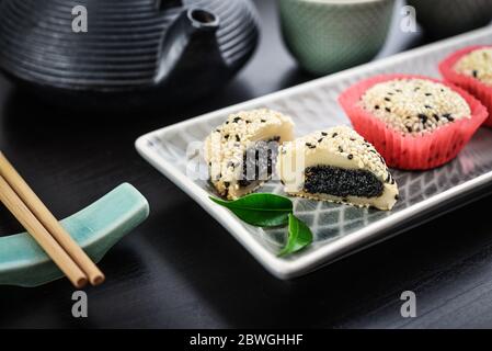 Mochi-Sortiment auf Teller mit Essstäbchen und grünem Tee - traditionelles japanisches Reisdessert, Nahaufnahme Stockfoto