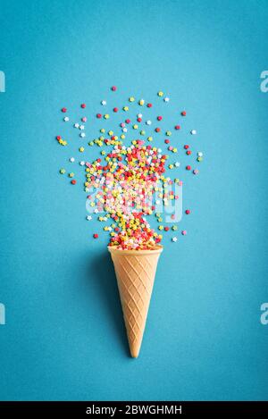 Konzept der Feier. Eiscreme-Konus mit bunten Sternen Konfetti auf blauem Hintergrund, Draufsicht Stockfoto