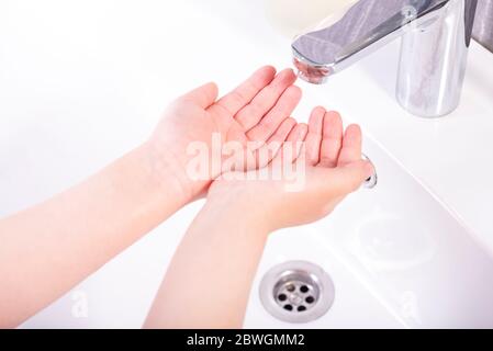 Waschen der Kinderhände mit der Seife unter dem Kran mit dem Wasser Stockfoto