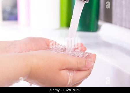 Waschen der Kinderhände mit der Seife unter dem Kran mit dem Wasser Stockfoto