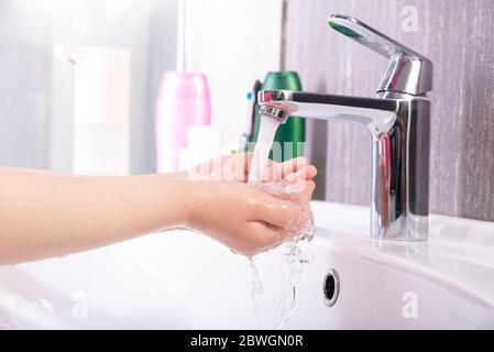 Waschen der Kinderhände mit der Seife unter dem Kran mit dem Wasser Stockfoto