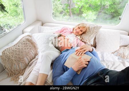 Glückliche reife Frau und ihr Mann entspannen auf dem Bett im Wohnmobil während Camping-Urlaub Stockfoto