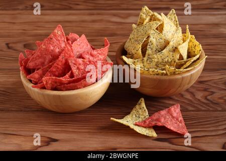 Tortilla Chips mit Chia Samen und Tortilla Chips mit Rote Bete in Bambusschüsseln auf Holztisch. Nahaufnahme Stockfoto