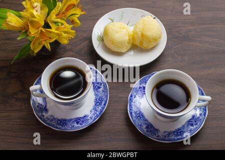 Brasilianisches Käsebrot und zwei Kaffeetassen auf dem dunklen Holztisch. Stockfoto