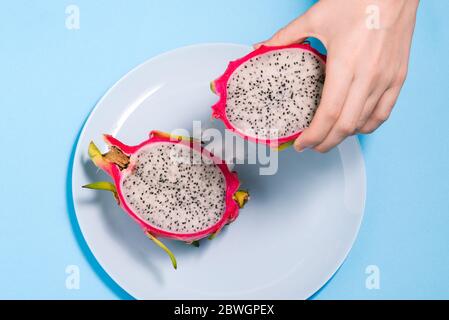 In Scheiben geschnittene Pitaya-Früchte. Die Hälfte der Pitaya liegt in der Hand eines Mannes. Drachenfrucht der Art Hylocereus undatus. Der Blick von oben. Stockfoto