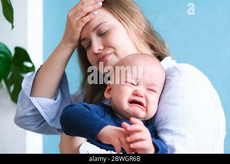 Mama müde versucht, ihr weinendes Baby zu beruhigen. Neugeborenes Tantrum Kind auf Mutterhand. Familienleben, Mutterschaft Stockfoto