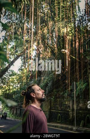 Porträt eines jungen Mannes mit Bart und langen Haaren in der Nähe der Straße in Ubud, Indonesien Stockfoto