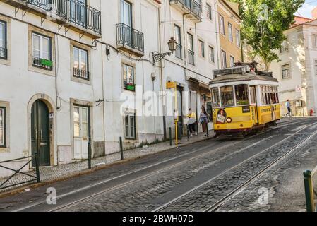 LISSABON, PORTUGAL - 2. JULI 2019: Straßenbahn auf dem hügeligen Gebiet der Altstadt, Sao Tome Straße in Alfama Bezirk ist der Teil der touristischen Route mit numerou Stockfoto