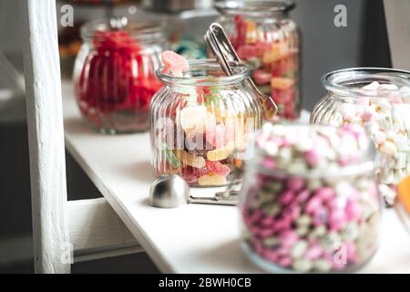 Bonbon Bar von mehreren Arten von bunten Süßigkeiten in Gläsern auf weißem Regal. Hochzeit oder Party Konzept. Stockfoto