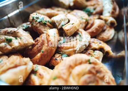 Haufen Käse und Speck wirbeln in Edelstahlbox. Gebackener salziger Snack. Selbstbedienungs-Buffet. Feier, Party, Geburtstag oder Hochzeit Konzept. Stockfoto