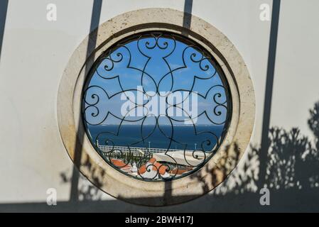 Blick vom Miradouro Santa Luzia durch ein rundes Fenster mit schmiedeeisernen Bildschirmen auf den Fluss im Stadtteil Alfama, Lissabon, Portugal Stockfoto