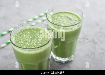 Grüner Smoothie mit Spinat oder Avocado in Glas auf grauem Hintergrund Stockfoto