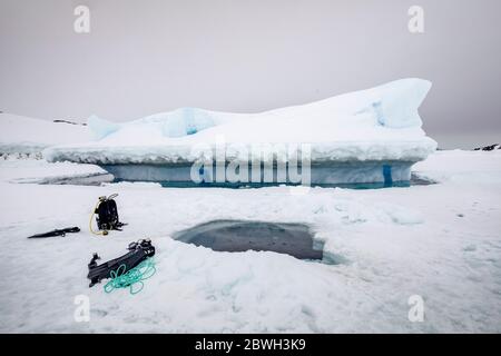 Die Spitze des Eisbergs tritt aus der gefrorenen Meeresoberfläche hervor, bewegt sich je nach Gezeiten auf und ab und hält das Wasser frei um ihn herum. Vor dem Stockfoto