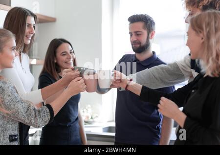 Freunde, die Teetassen halten, klirren in der Küche zusammen Stockfoto