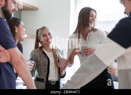 Lächelnde Freunde treffen sich mit Tassen Tee Stockfoto