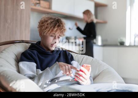 Glücklicher Mann, der Phonett in der Küche benutzt Stockfoto