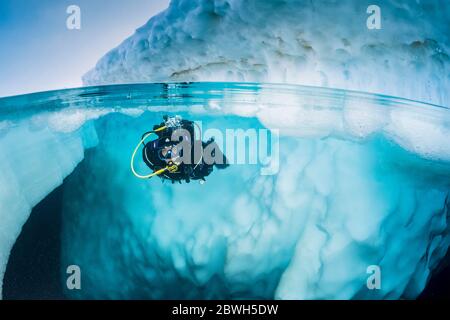 Spit Bild eines Scuba Diver tauchen in der Nähe von einem Eisberg, nur im Frühling, wenn der Winter langsam nachlässt, sind die Eis-kalten Gewässern geeignet für Stockfoto