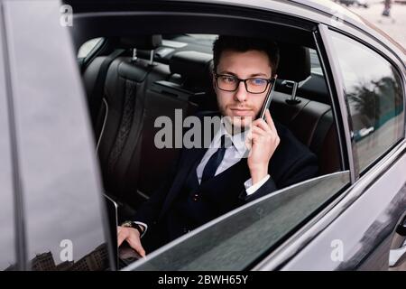 Junger Geschäftsmann im Auto mit Smartphone sprechen Stockfoto