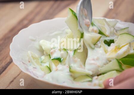 Mischen von grünen Apfelstücken mit der Banane und Müsli in Joghurt Stockfoto