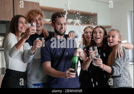 Fröhliche junge Freunde, die eine Flasche Champagner öffnen Stockfoto